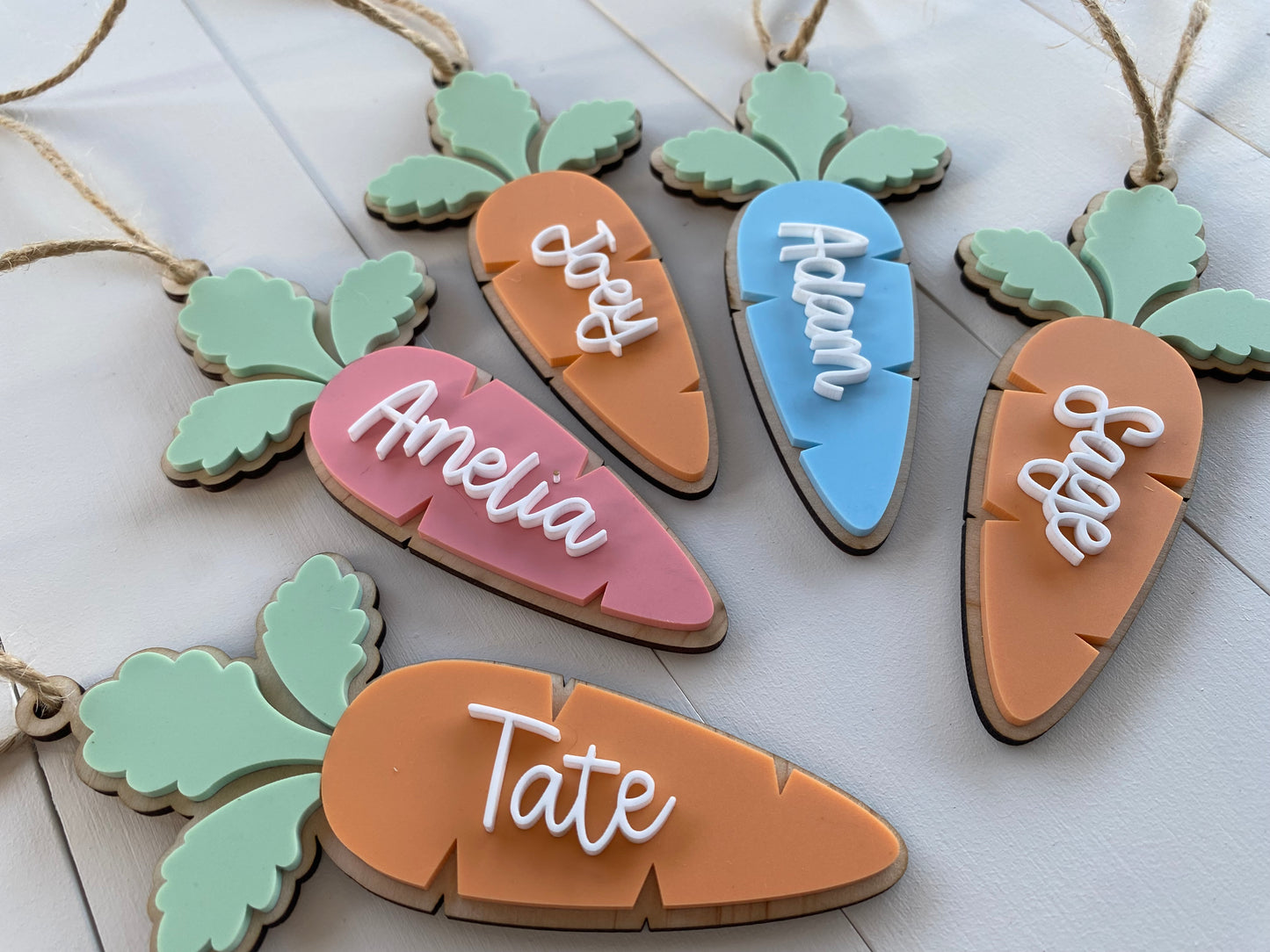 Carrot-shaped name tags with names 'Amelia', 'Tate', and 'Sage' on a light wooden surface.