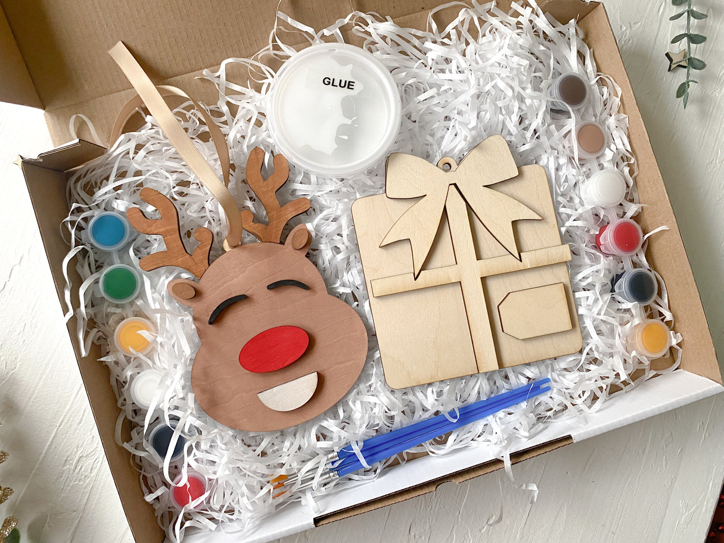 Wooden reindeer craft kit with paint, glue, and tools in a box.