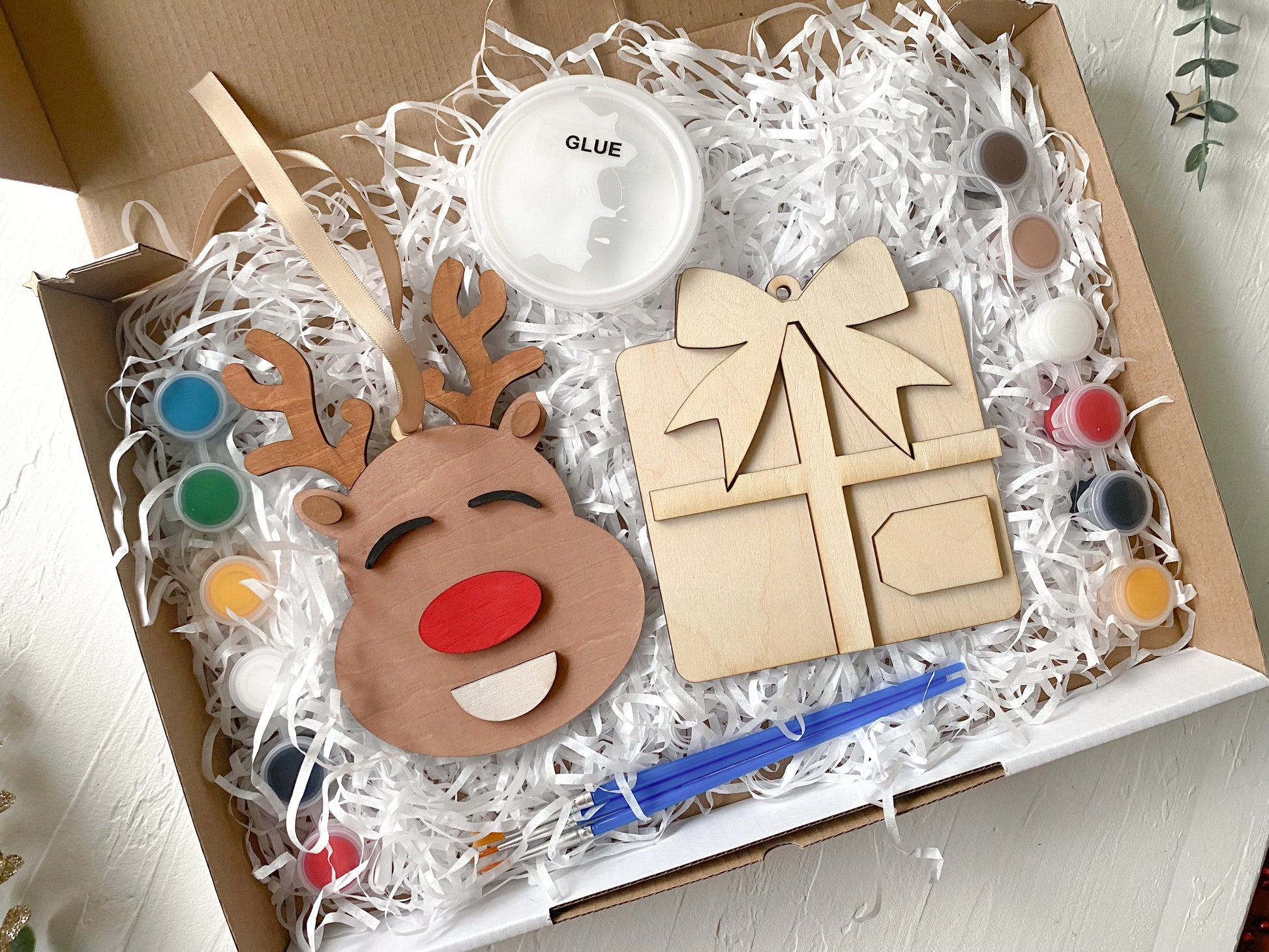 Wooden reindeer craft kit with paint, glue, and tools in a box.